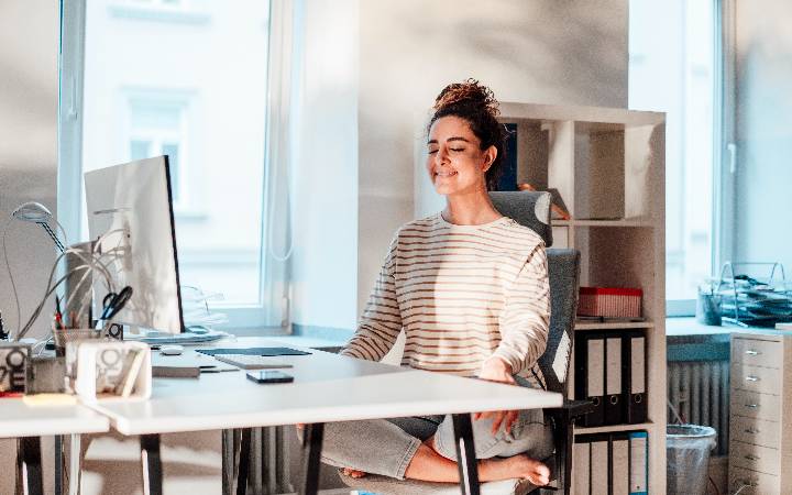 businesswoman meditating at desk in office