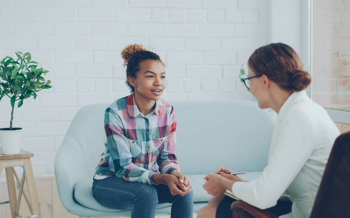 girl talking to psychologist sitting on sofa